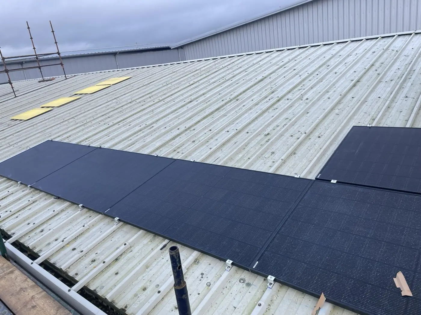 A new row of black solar panels on a corrugated metal commercial roof