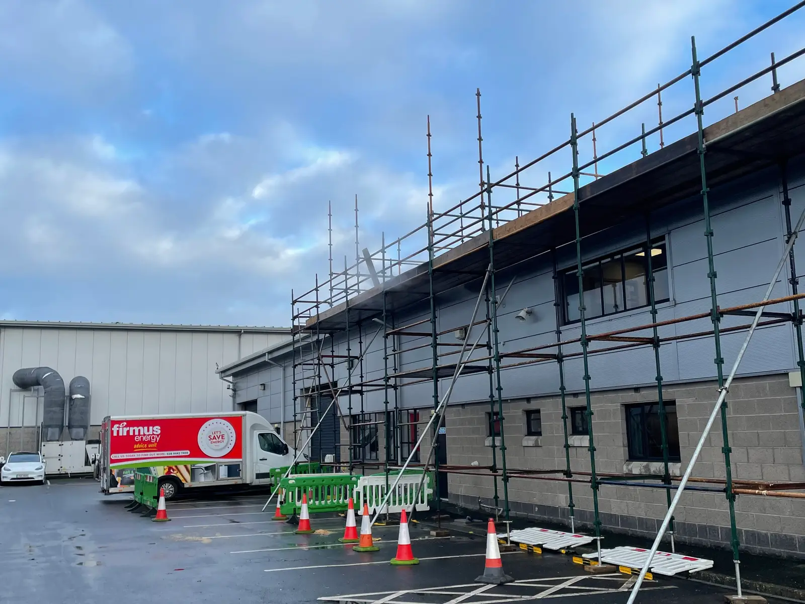 Scaffolding along the front of Firmus Energy's office building in Antrim, with a Firmus Energy van in the car park