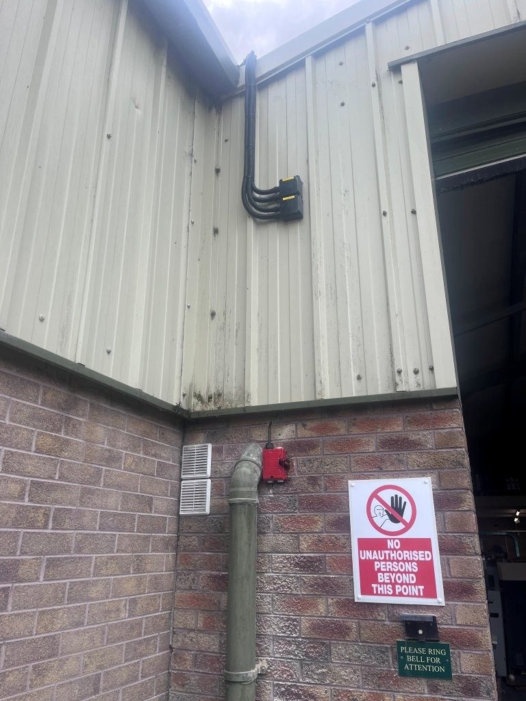 External DC isolators and the red firefighter emergency switch mounted on the outside wall of The Print Factory