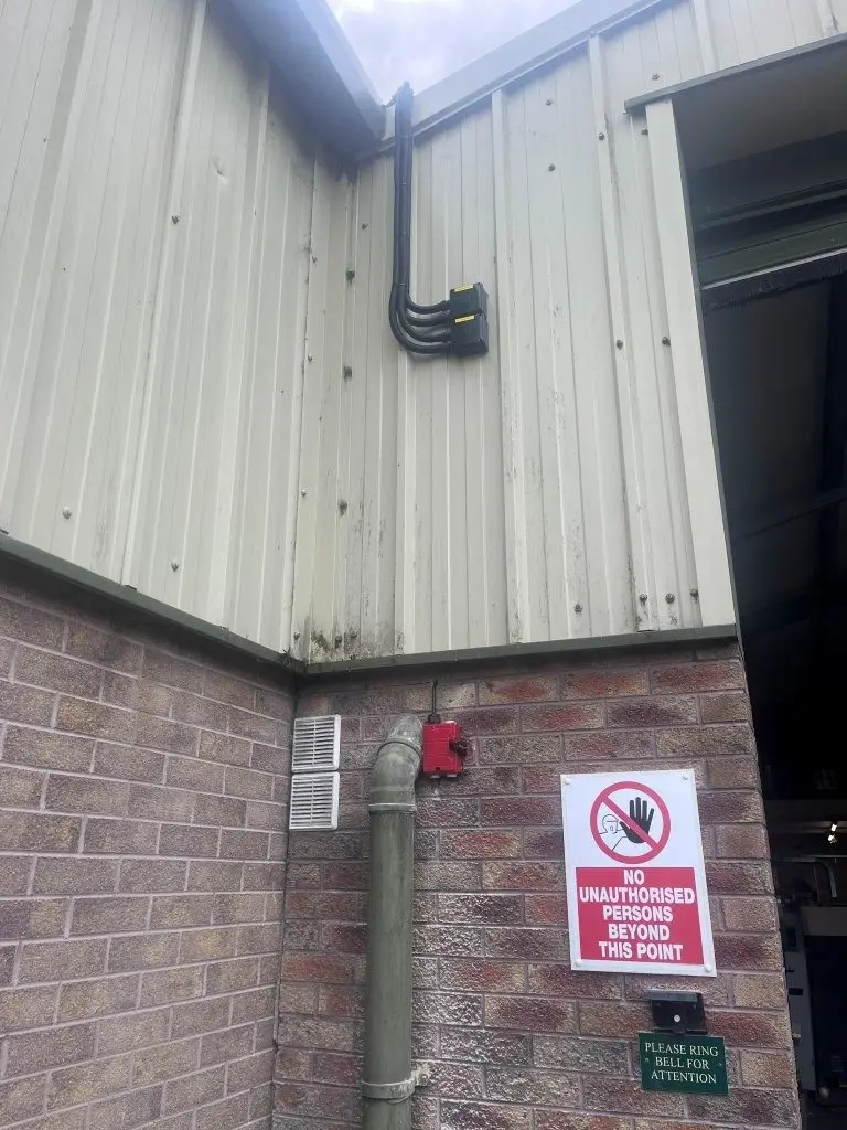 External DC isolators and the red firefighter emergency switch mounted on the outside wall of The Print Factory