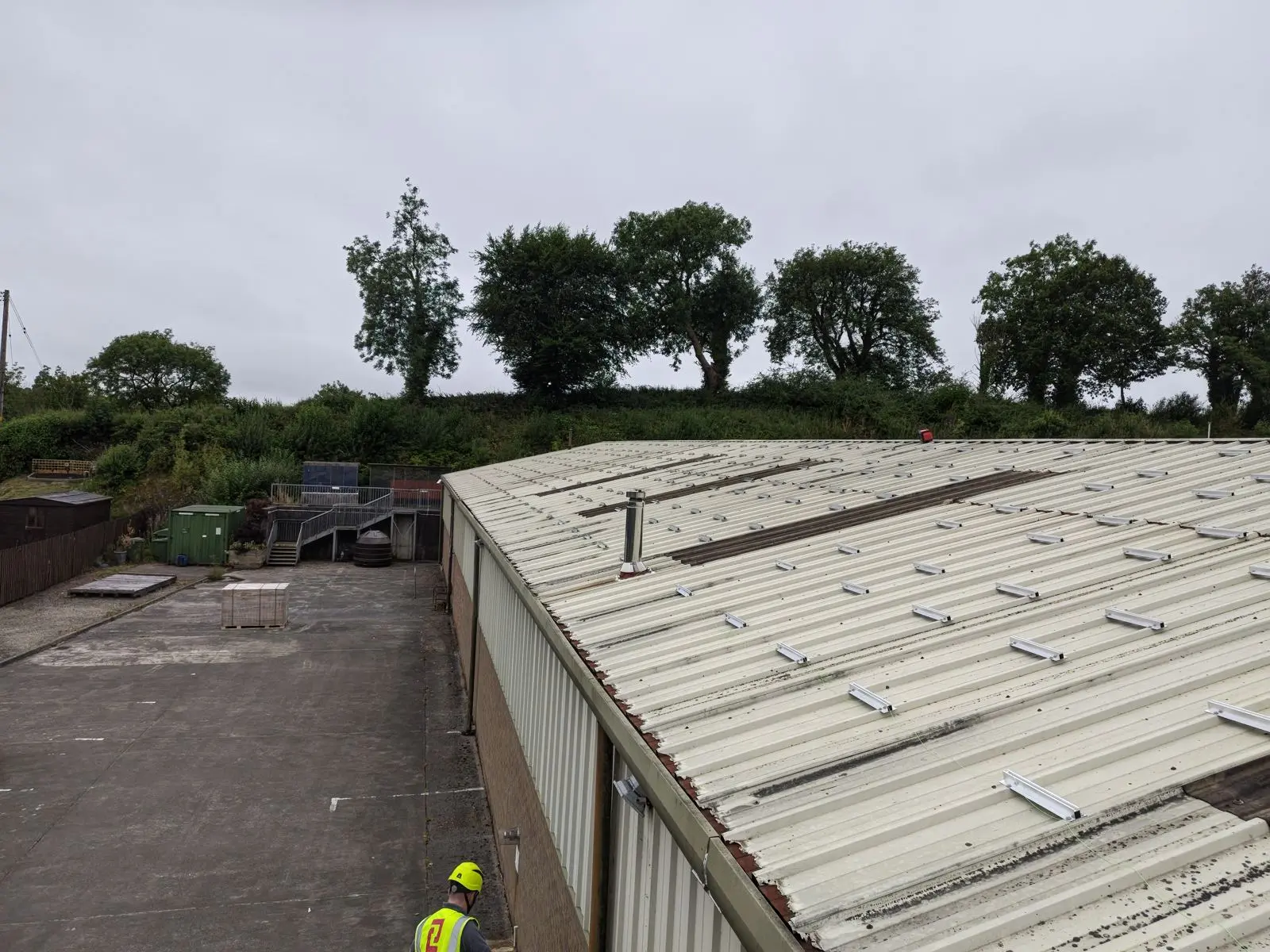 Mounting rails being set out across the bare steel roof of The Print Factory on install day, an installer in a hard hat in the foreground