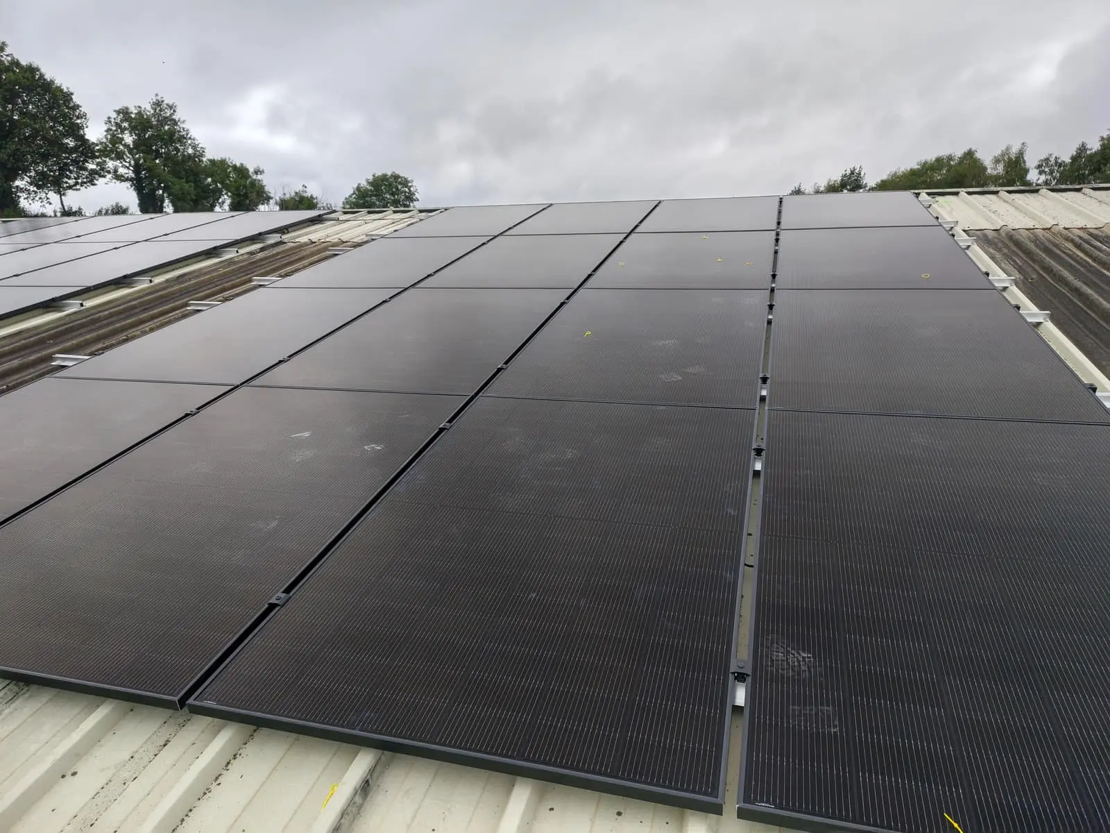 Close view up the finished rows of all-black solar panels on The Print Factory roof under an overcast sky