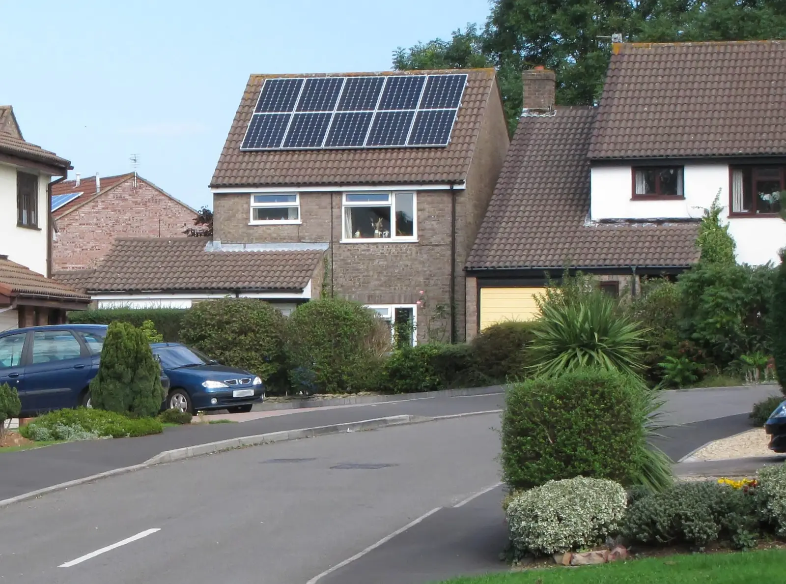 A detached house with solar panels on the roof slope that faces the street